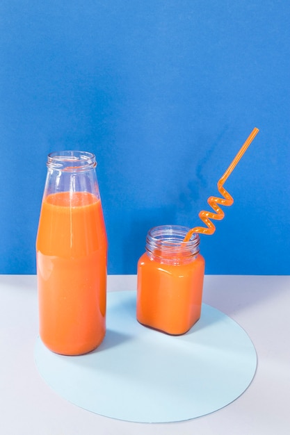 Botella con batido de naranja en la mesa