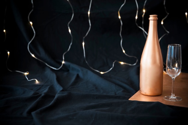 Foto gratuita botella de champagne con copa en mesa