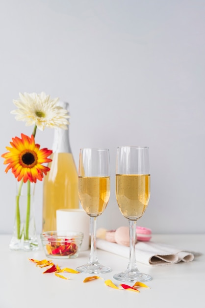 Foto gratuita botella de champagne con copas y flores.