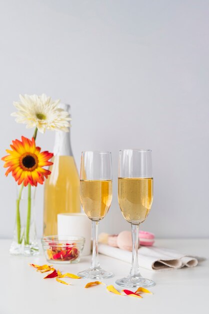 Botella de champagne con copas y flores.