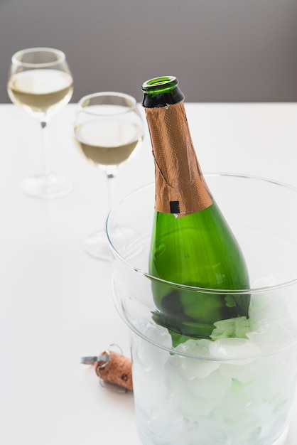 Botella de champagne con hielo y vasos.