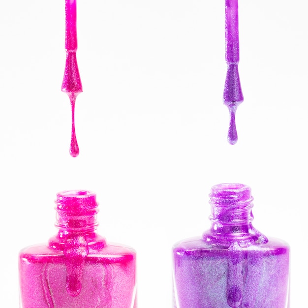 Botella de esmalte de uñas rosa y púrpura sobre fondo blanco