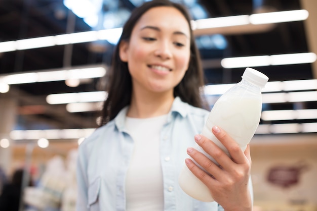 Botella de explotación femenina asiática alegre de leche en el supermercado