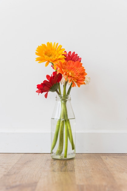 Botella con flores de pie en el piso