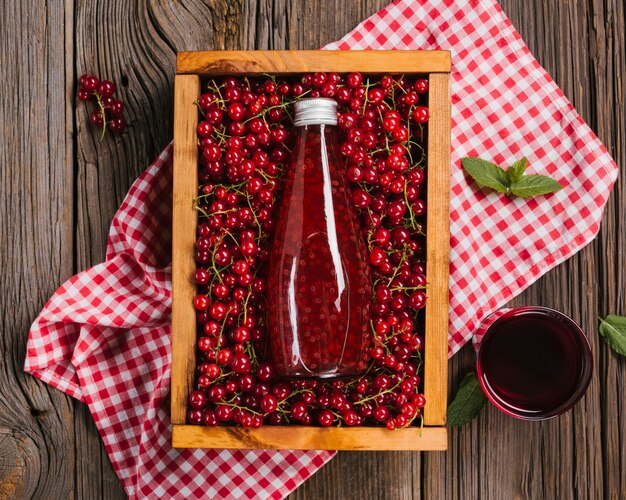 Botella de jugo de arándano sobre fondo de madera