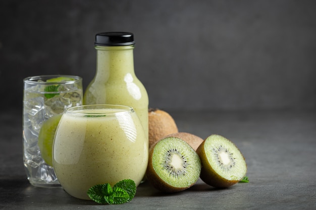 Foto gratuita botella de jugo de kiwi en piso oscuro