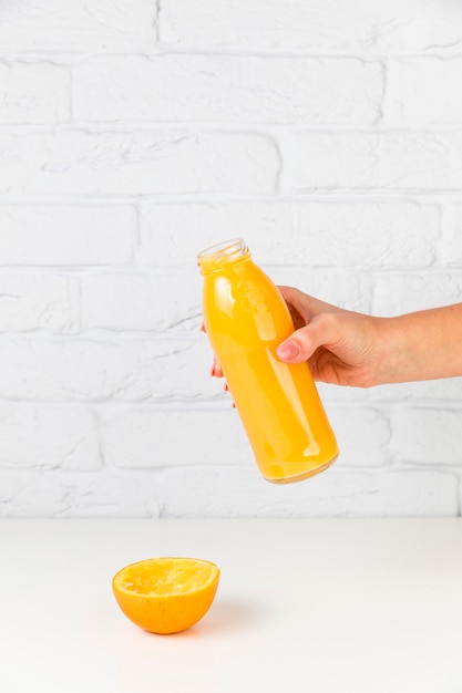 Foto gratuita botella de jugo de naranja fresco celebrada por persona
