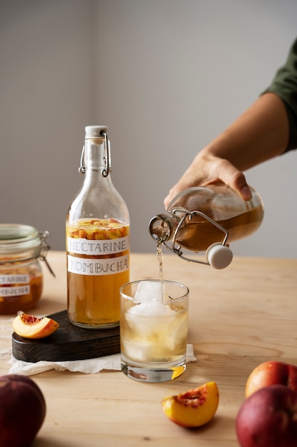 Botella de kombucha de nectarina y vaso con hielo