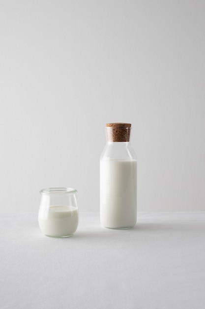 Botella de leche y arreglo de vidrio con fondo blanco.