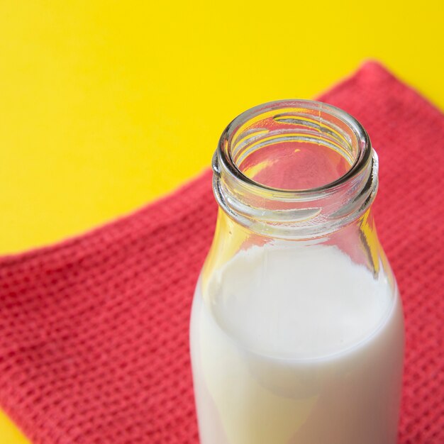 Botella de leche en la servilleta roja sobre el fondo amarillo