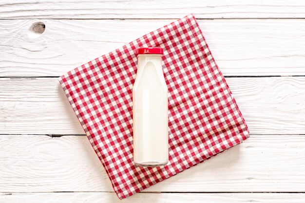 Foto gratuita botella de leche sobre un fondo blanco de madera endecha plana
