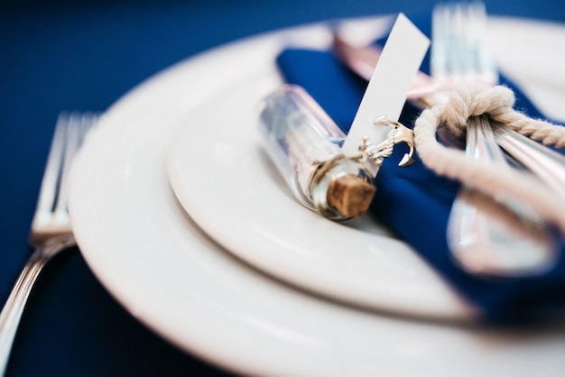 Botella con una letra se encuentra en la servilleta azul en la mesa de la cena