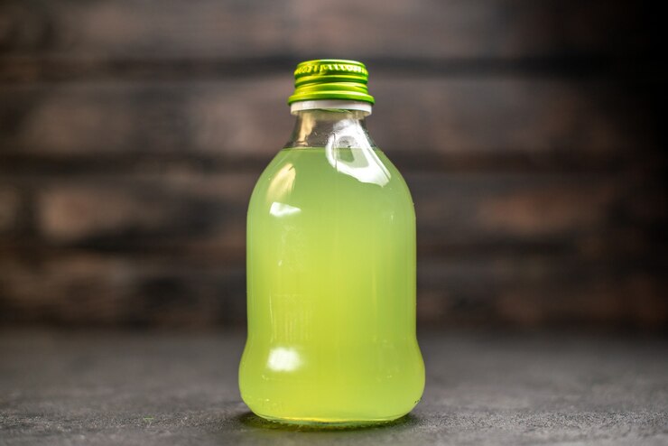 Foto gratuito botella de limonada de frente en superficie de madera