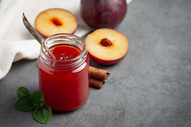 Botella de mermelada de ciruela puesta en piso oscuro