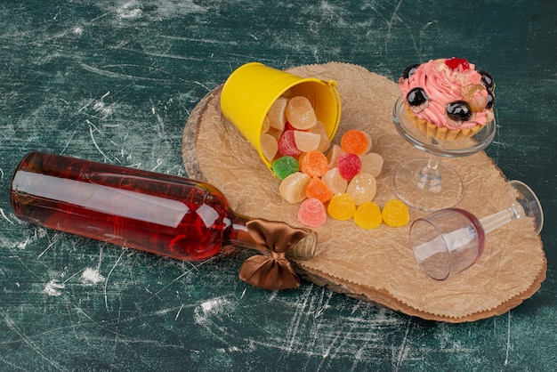 Botella con placa de vidrio de donut y caramelos de gelatina en tablero de madera