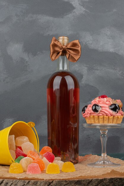 Botella con placa de vidrio de donut y caramelos de gelatina en tablero de madera