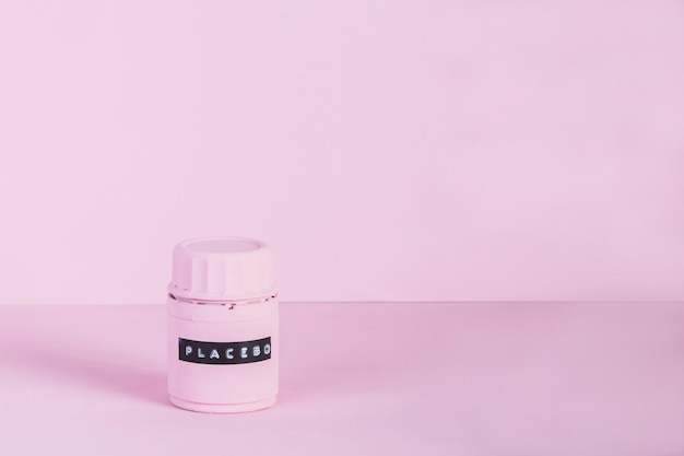 Botella de Placebo con etiqueta contra fondo rosa
