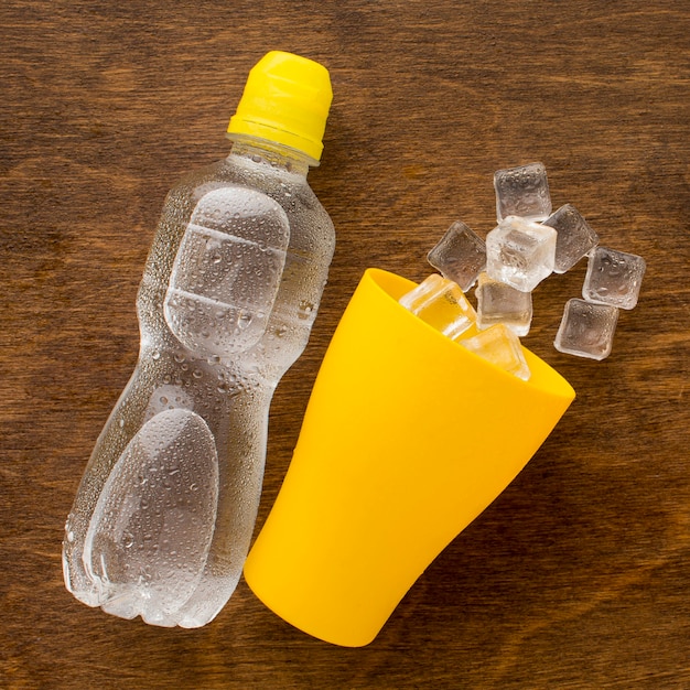 Foto gratuita botella de plástico de agua y hielo en taza