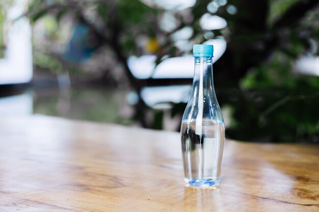 Botella de plástico de agua sobre la mesa de madera