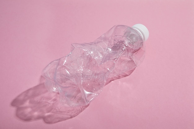 Botella de plástico reciclada sobre fondo de color rosa