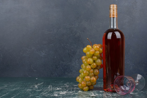 Botella roja con uvas y vaso vacío