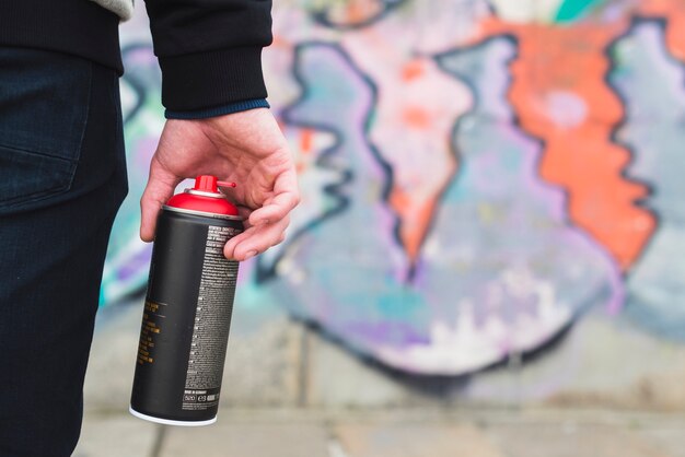 Botella de spray aerosol en mano de artista