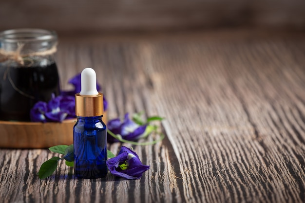 Botella de suero de aceite de flor de guisante de mariposa sobre fondo de madera