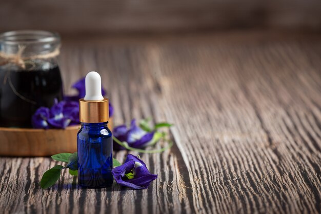 Botella de suero de aceite de flor de guisante de mariposa sobre fondo de madera