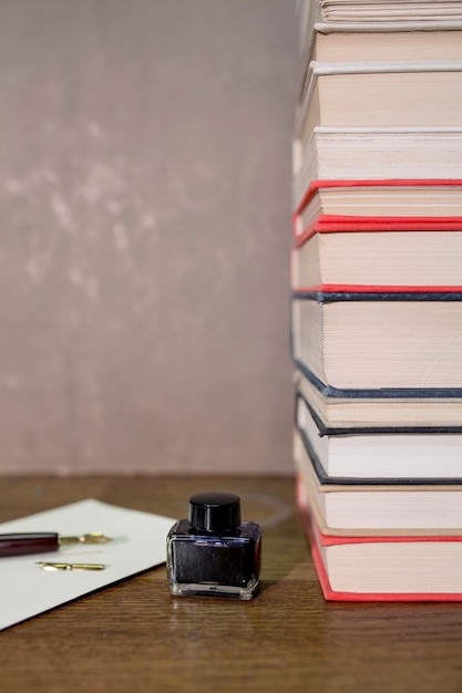 Foto gratuita botella de tinta cerca de la pila de libros