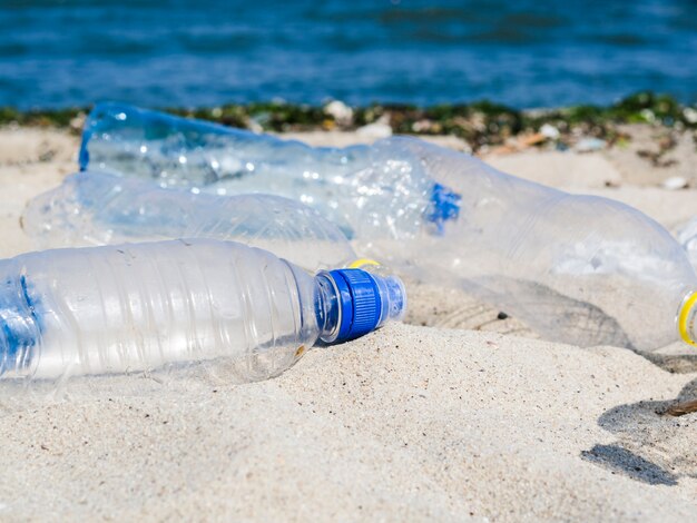 Botella vacía de aguas residuales en la arena en la playa