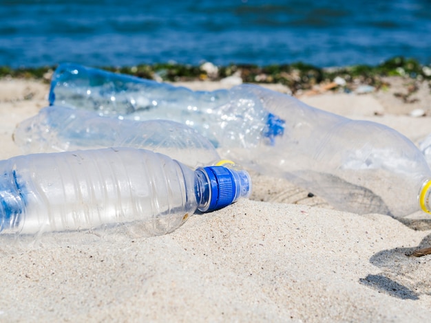 Botella vacía de aguas residuales en la arena en la playa