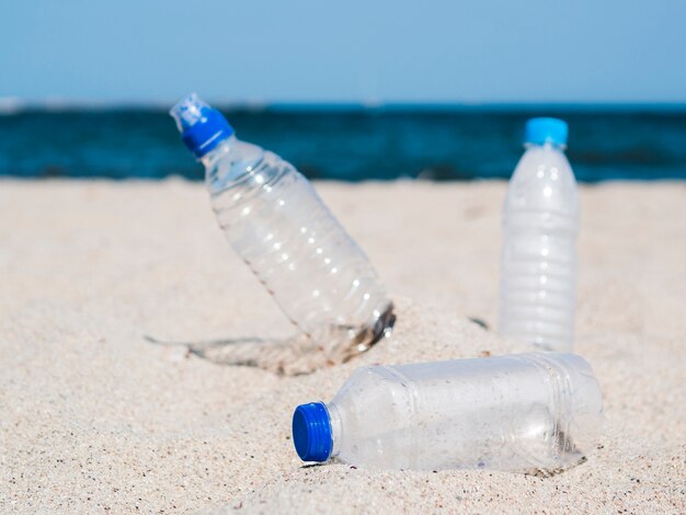 Botella vacía de residuos plásticos en la arena en la playa