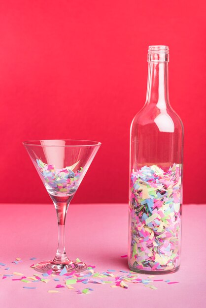 Botella y vaso con confeti de colores