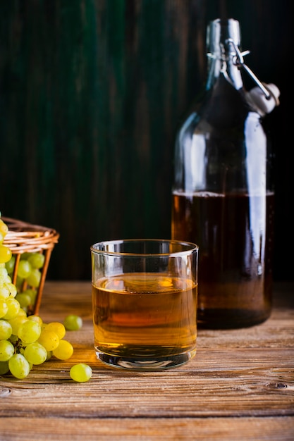 Botella y vaso en la mesa con jugo de uvas frescas