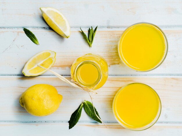 Botella y vasos de bebida amarilla con limón fresco y menta.