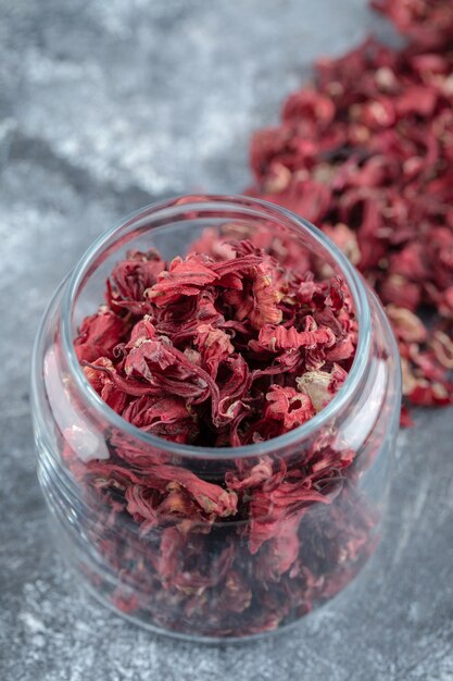 Botella de vidrio de pétalos de flores secas sobre la mesa de mármol.