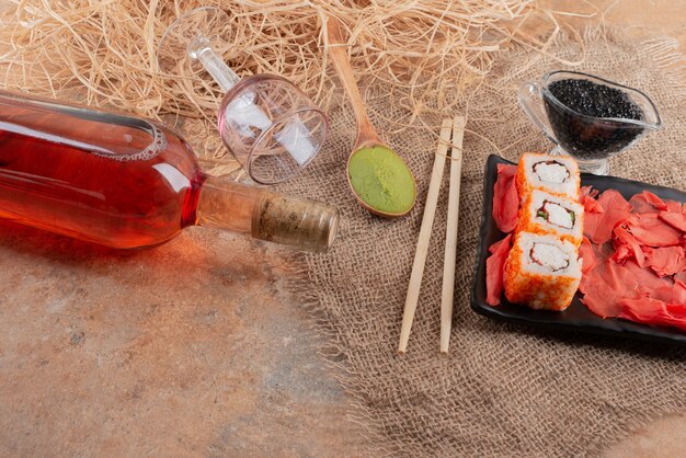 Botella de vino con copa de vino y sushi sobre arpillera