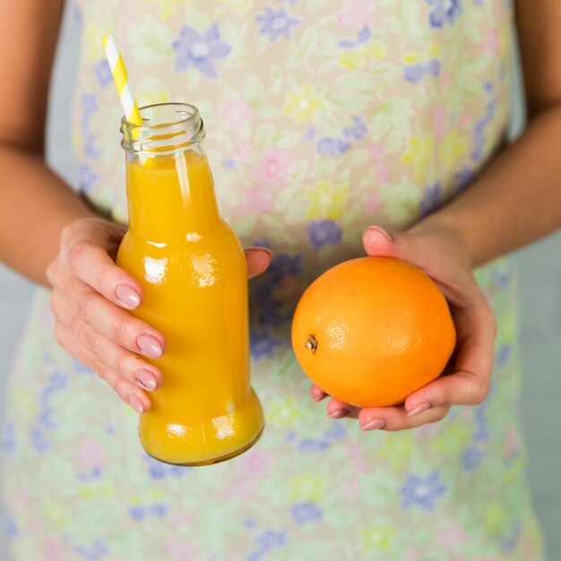 Botella de zumo de naranja natural y naranja.