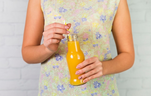 Botella de zumo de naranja natural en poder de una mujer.