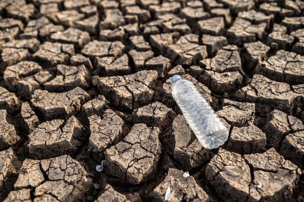 Botellas de agua en suelo seco con suelo seco y agrietado, calentamiento global