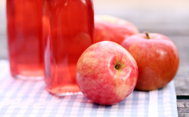 Botellas con bebidas rojas y algunas manzanas.