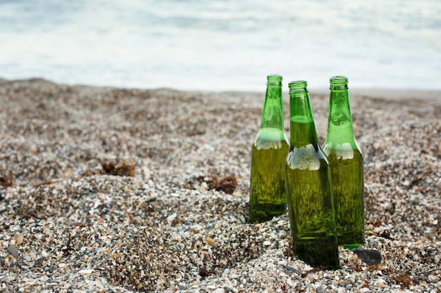 Botellas de cerveza al aire libre en la arena de la playa con espacio de copia
