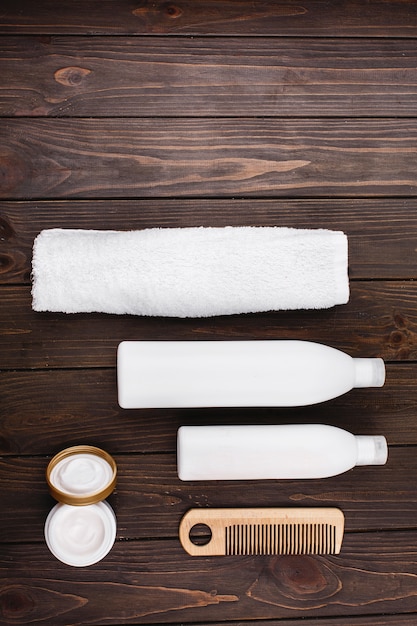Botellas de champú y acondicionador se encuentran con una toalla y peine en la mesa de madera