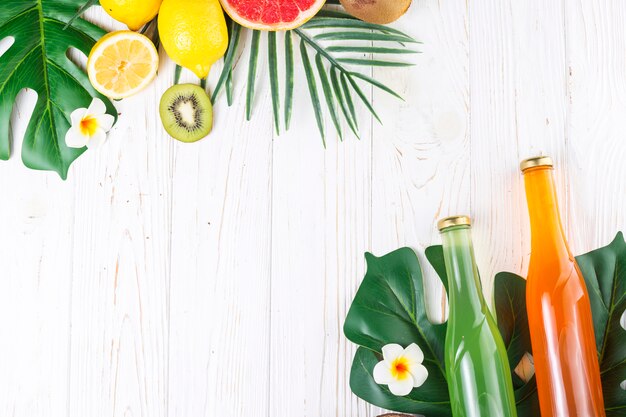 Botellas de colores con bebidas y varias frutas.