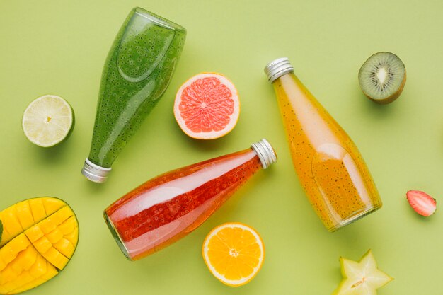 Botellas de jugo de colores y rodajas de fruta