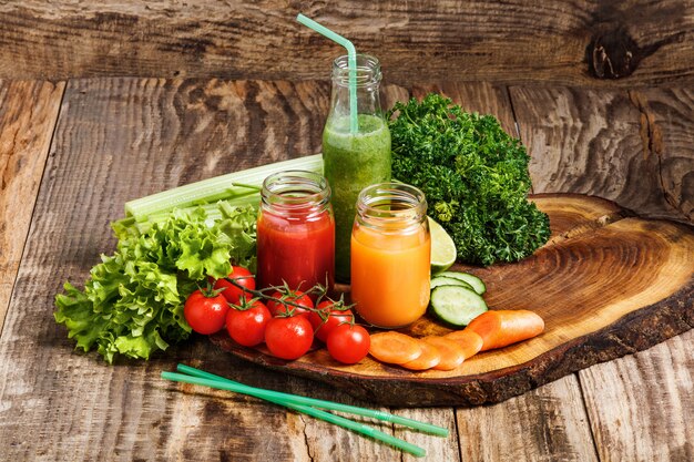 botellas con jugos de vegetales frescos en la mesa de madera