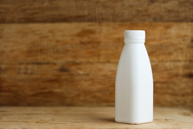 Botellas de leche de plástico blanco sobre fondo de tabla de madera retro