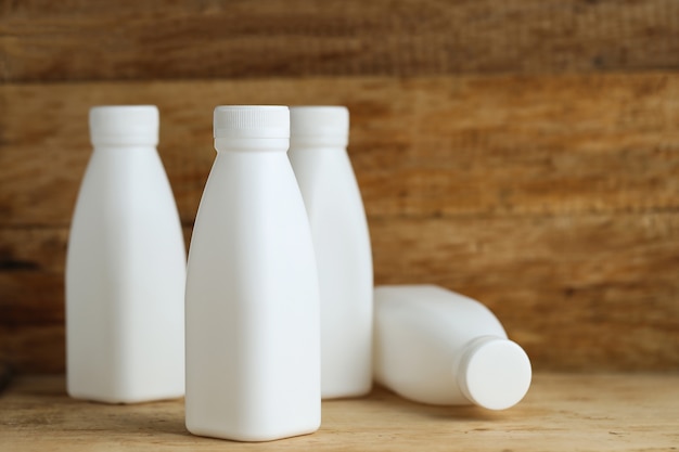 Botellas de leche de plástico blanco sobre fondo de tabla de madera retro