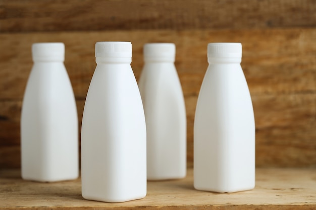 Botellas de leche de plástico blanco sobre fondo de tabla de madera retro