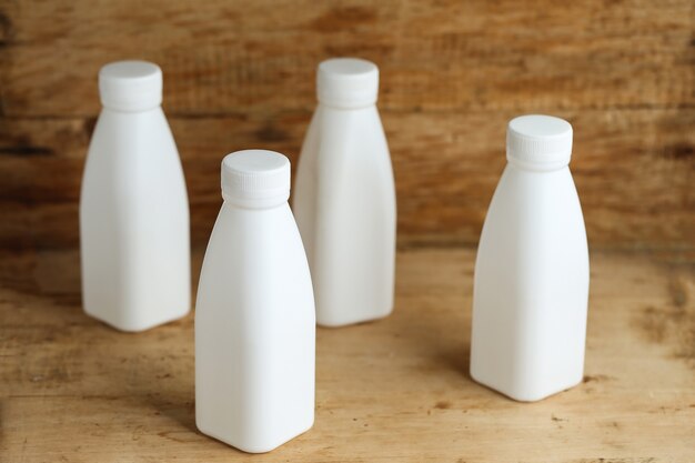 Botellas de leche de plástico blanco sobre fondo de tabla de madera retro